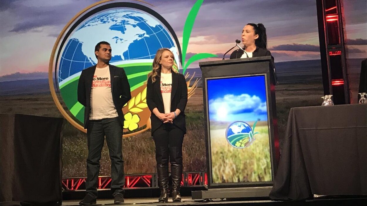 Les trois fondateurs son sur une scène où on voit en arrière-plan un grand champ et une carte de l'amérique du nord, une femme se tient derrière le podium de la conférence FarmTech.