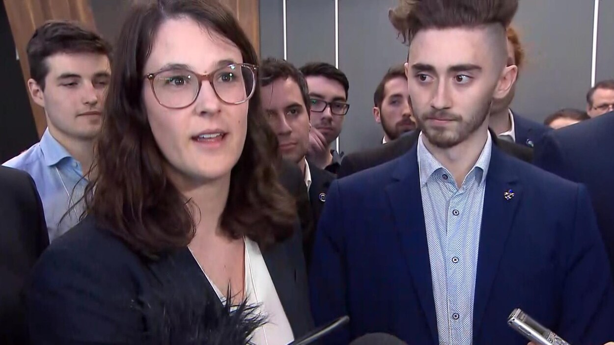 La présidente du Comité jeunesse du PQ parle aux journalistes entourée d'autres personnes.