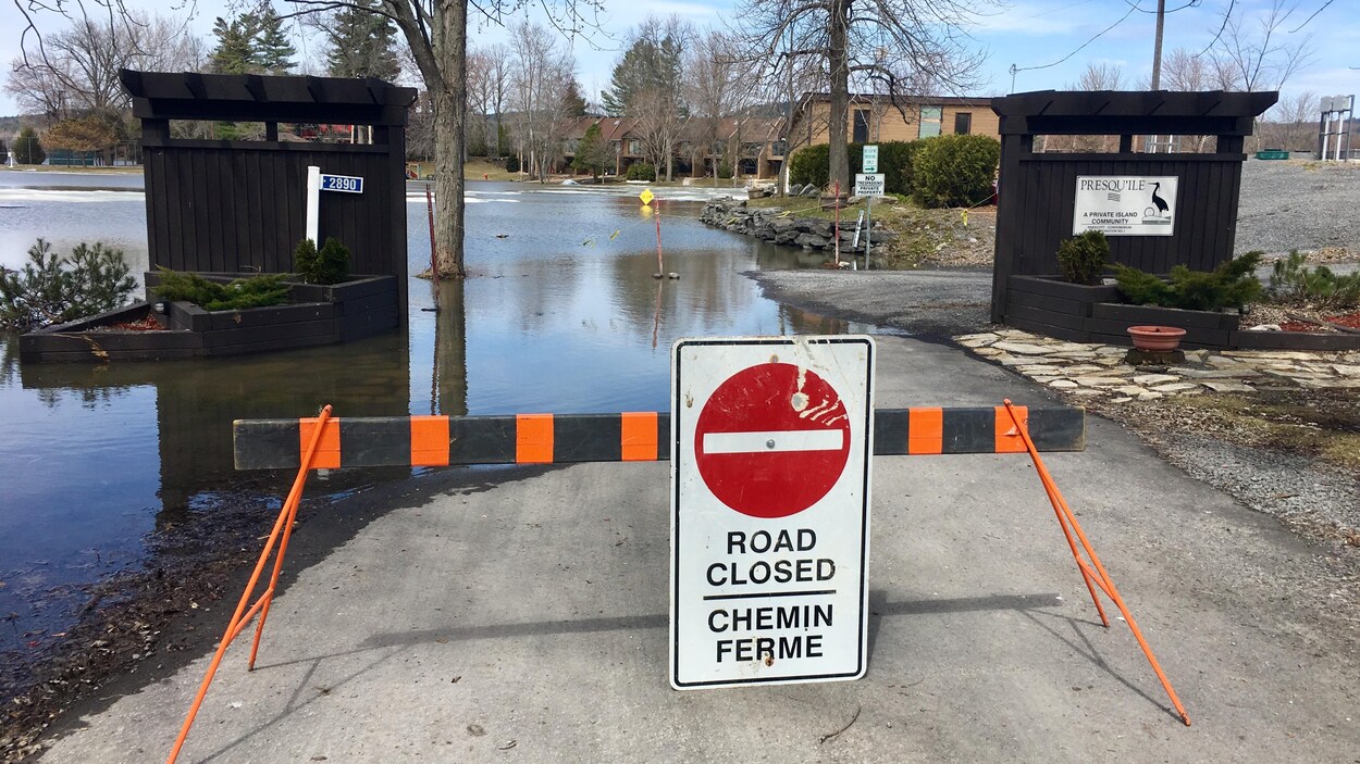 Un panneau ferme l'accès à une route inondée.
