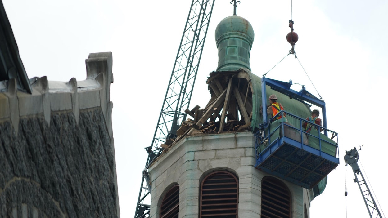 Des travailleurs sur une nacelle au haut d'une église