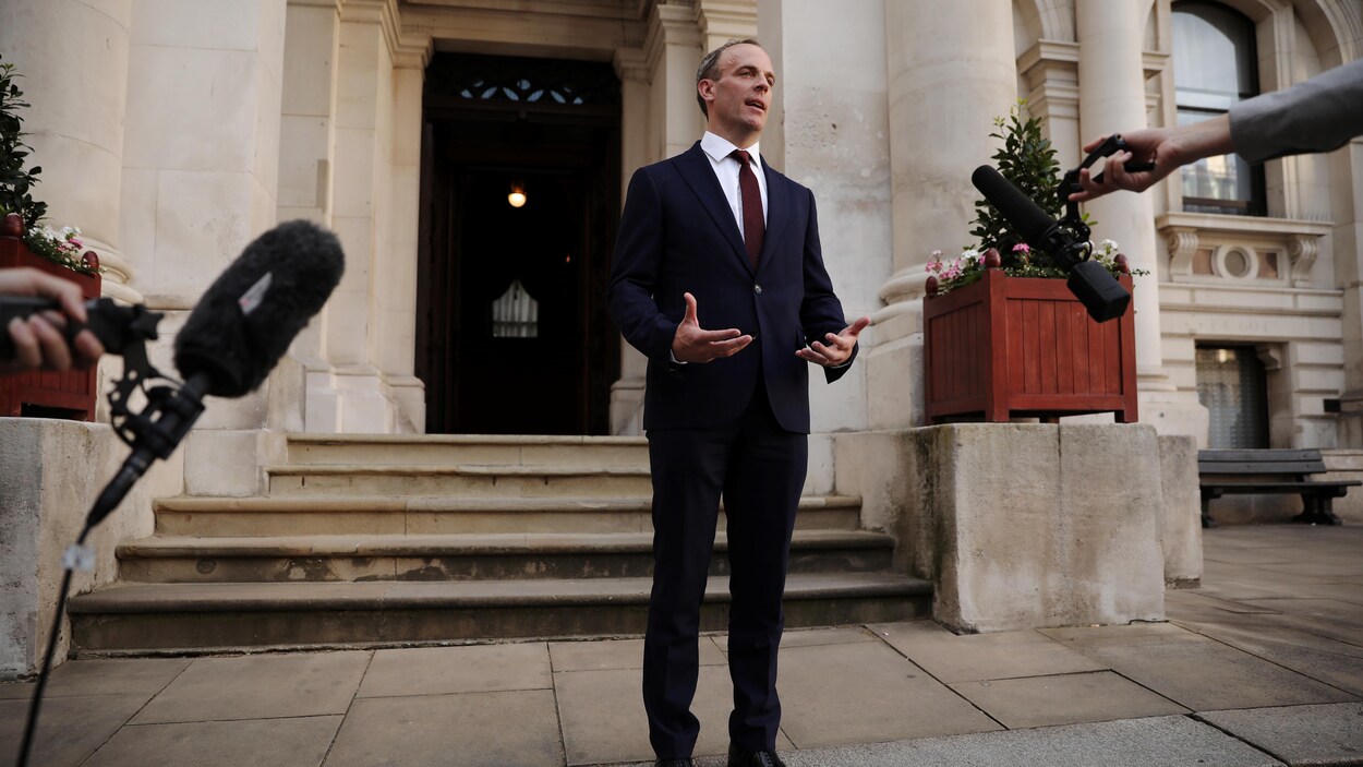 M. Raab parle devant la façade d'un bâtiment.