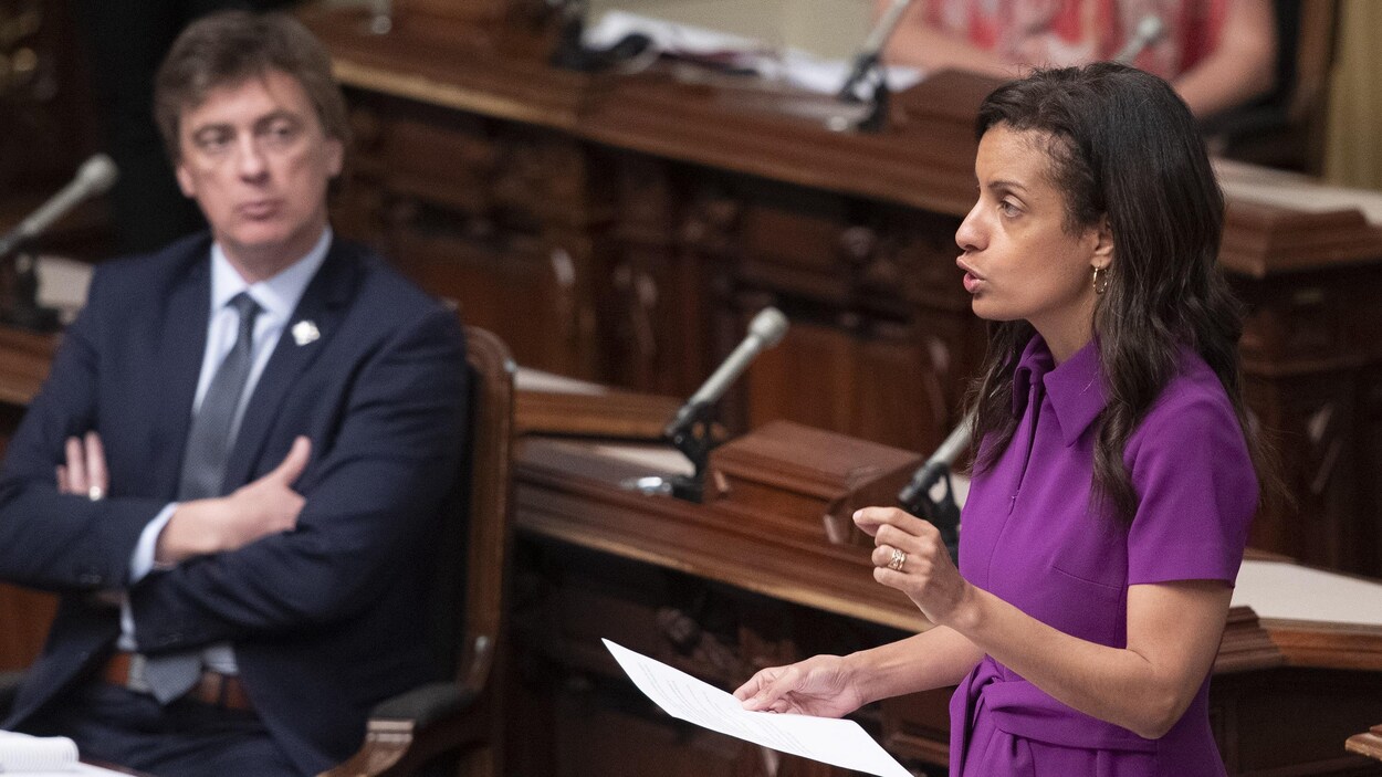 Dominique Anglade, debout s'adresse à l'assemblée. Marc Tanguay est assis à l'arrière plan.