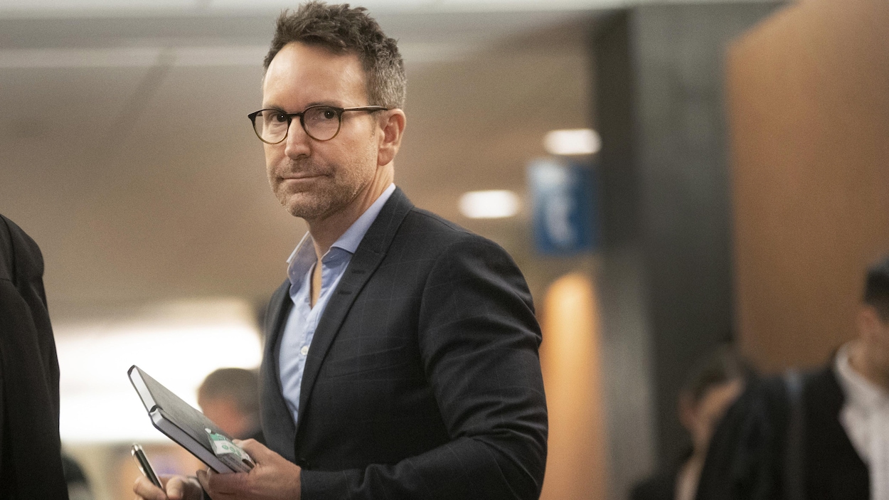 Éric Salvail tient dans ses mains un carnet et un crayon.