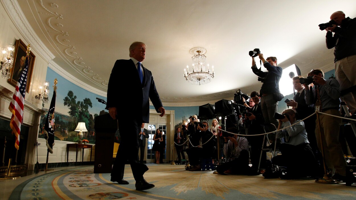 Donald Trump marche à la Maison-Blanche, devant des membres de la presse.