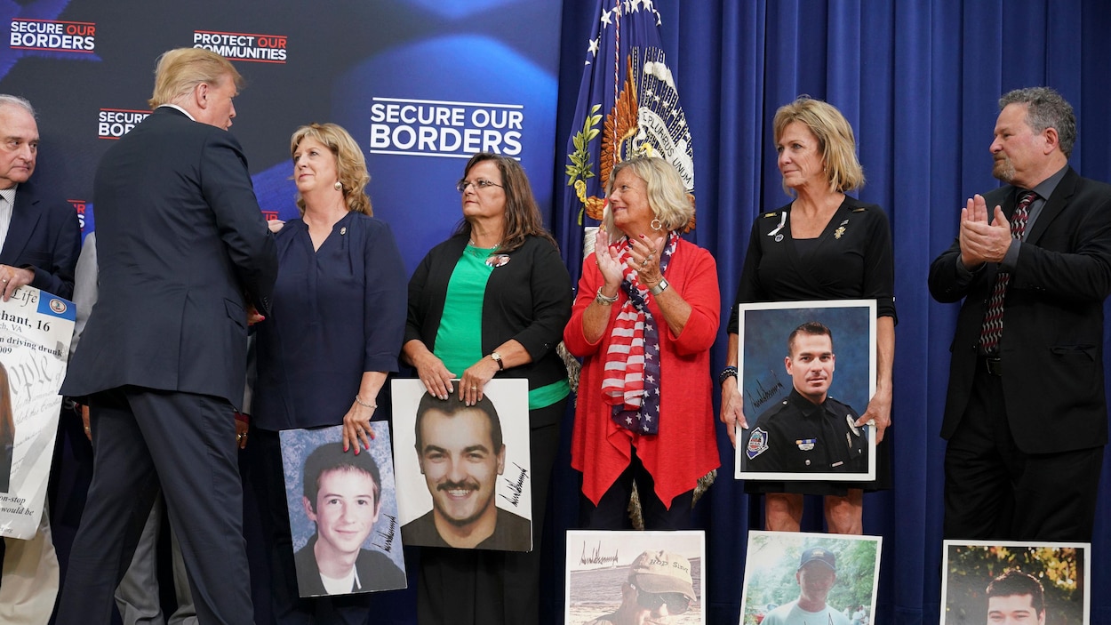 Donald Trump serre la main de gens tenant des photos grand format de gens assassinés. Donald Trump serre la main de gens tenant des photos grand format de gens assassinés.