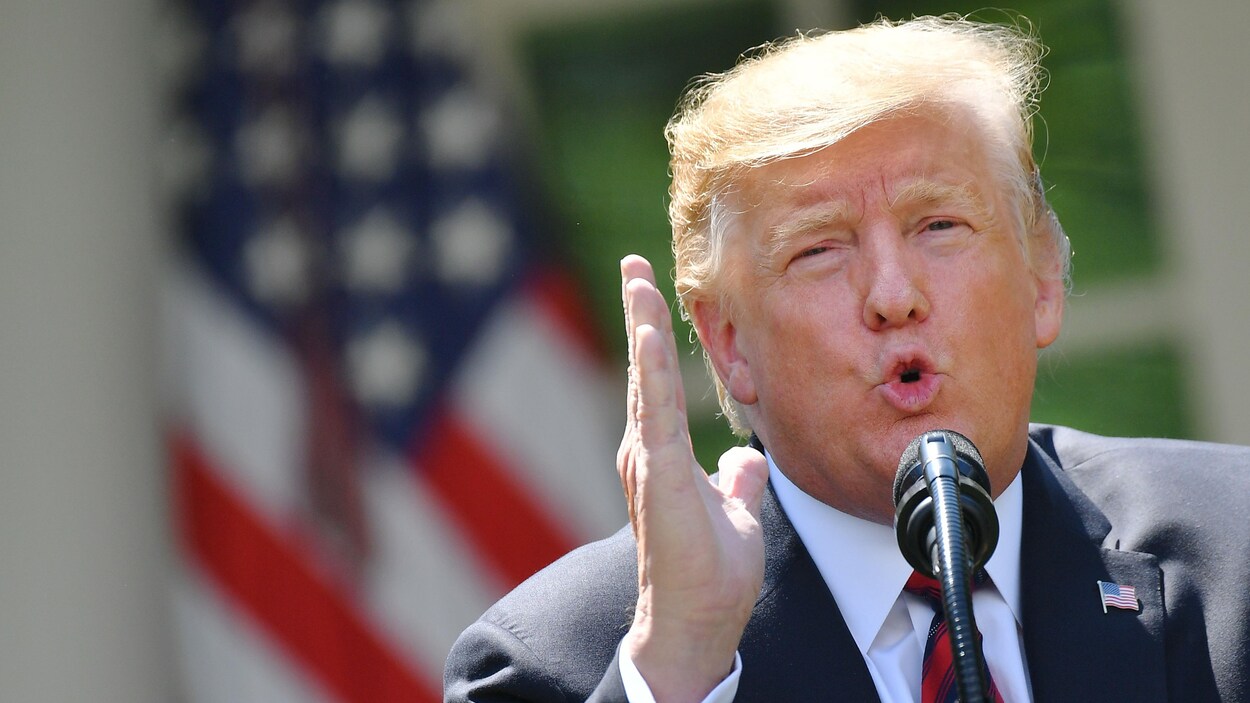 Le président américain lève une main et a la bouche en forme de O.