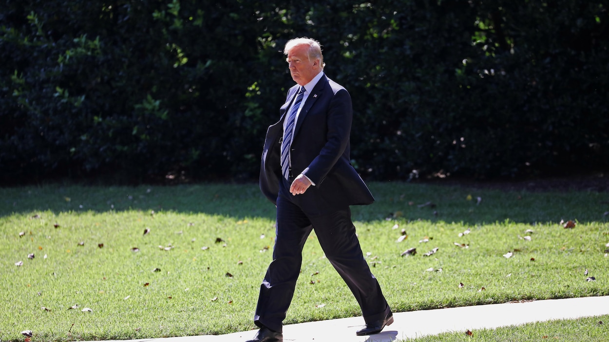 Donald Trump marche sur un terrain gazonné.