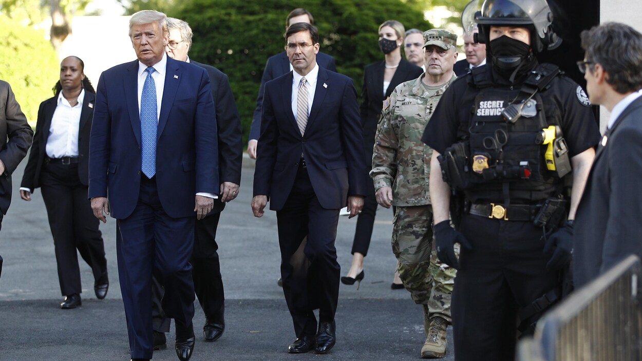 Donald Trump, entouré de plusieurs personnes, marche à l'extérieur.