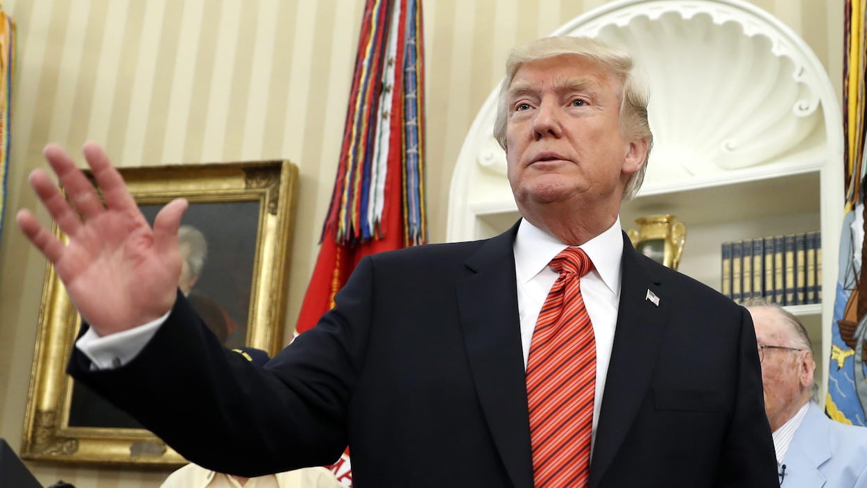 Donald Trump se tient dans le Bureau oval de la Maison-Blanche et tend une main devant lui, comme s'il saluait. Donald Trump se tient dans le Bureau oval de la Maison-Blanche et tend une main devant lui, comme s'il saluait.