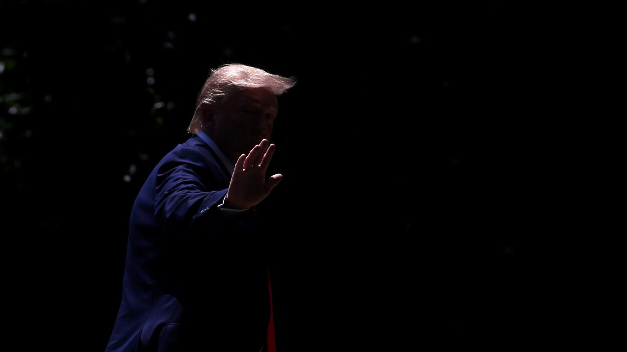 On ne distingue que la chevelure et la main de M. Trump sur cette photo prise dans la pénombre.