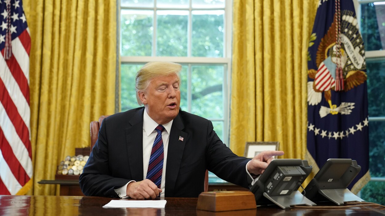 Trump compose un numéro sur son téléphone pendant qu'il est assis dans le bureau ovale à la Maison-Blanche.