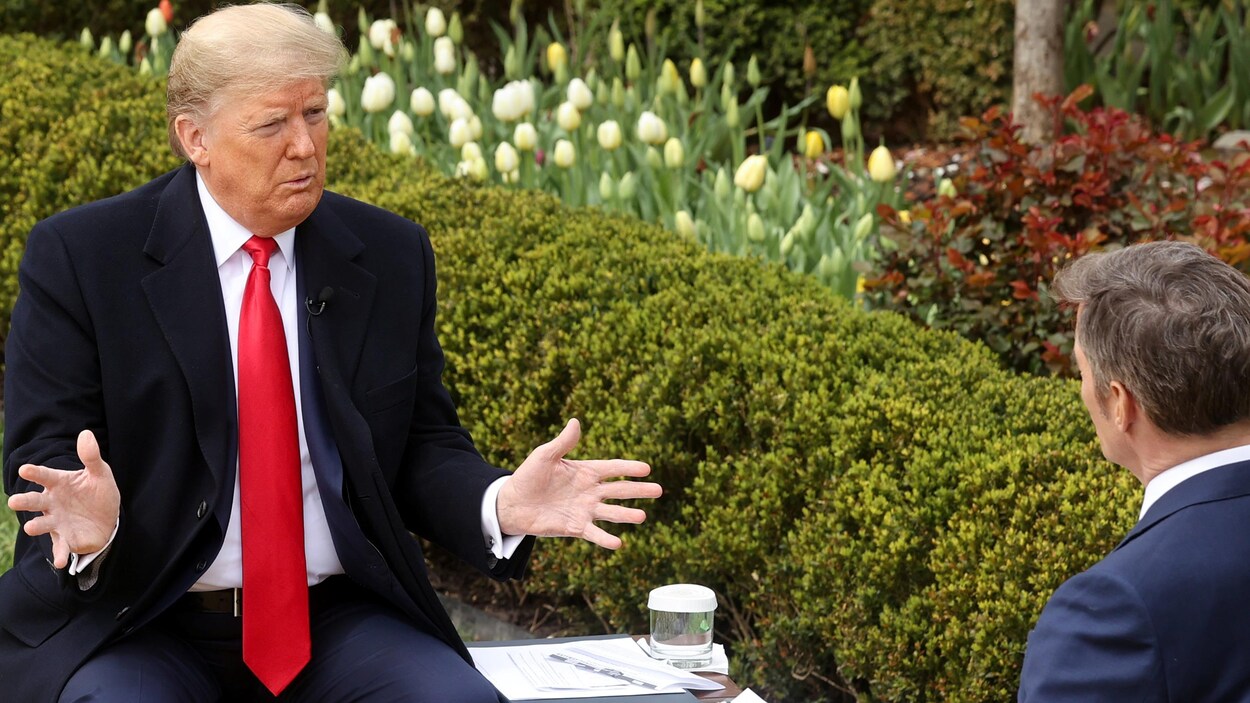 Donald Trump, assis sur un banc, s'adresse à un journaliste vu de dos.