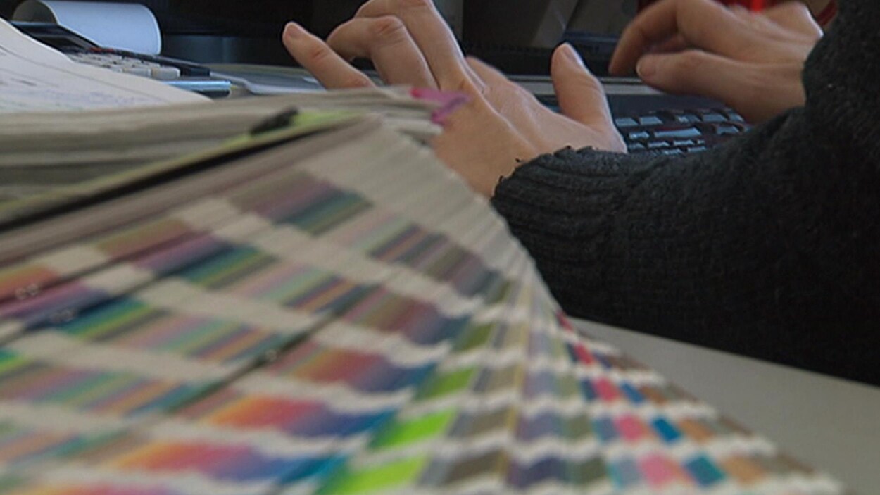 Une personne tape sur un clavier d'ordinateur, une pile de dossiers est déposée sur son bureau. Une personne tape sur un clavier d'ordinateur, une pile de dossiers est déposée sur son bureau.