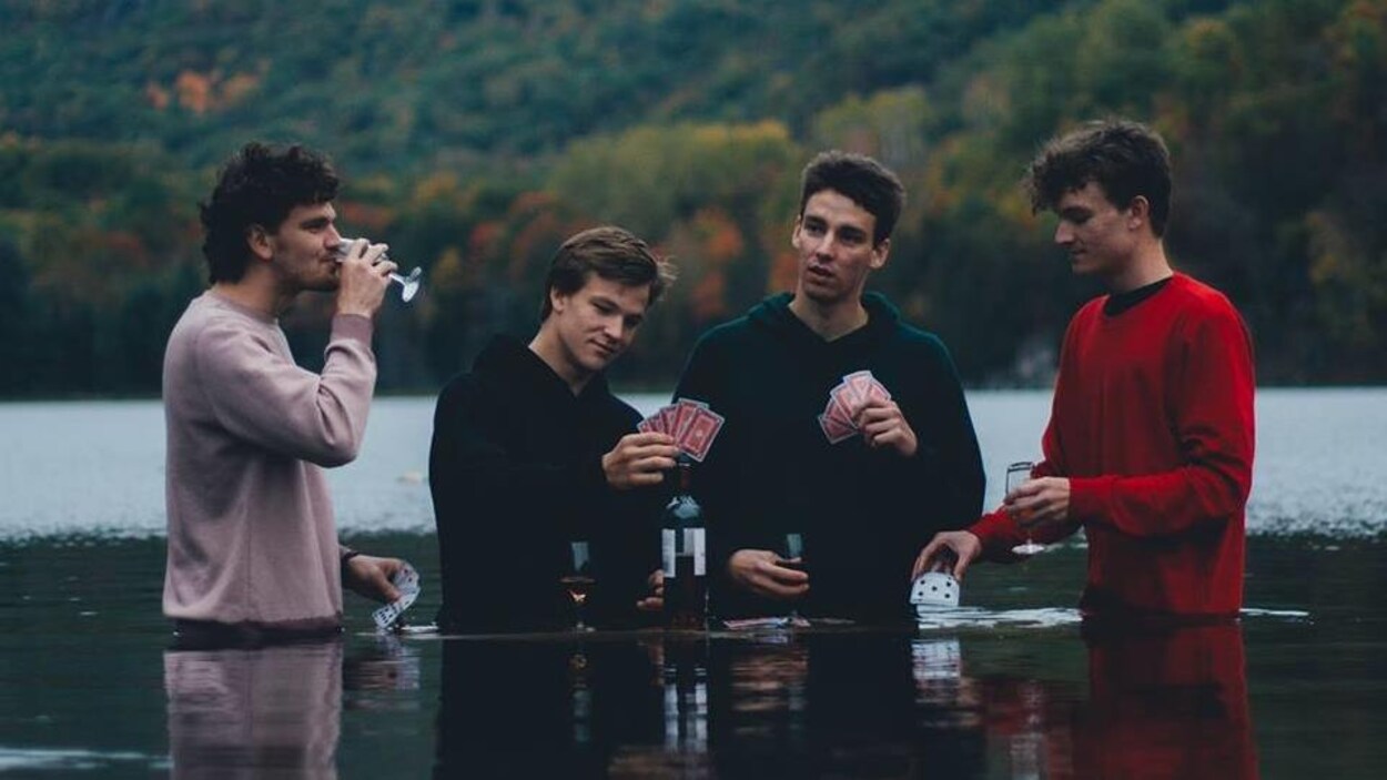 Quatre jeunes hommes dans un lac avec de l'eau jusqu'à la moitié du corps Quatre jeunes hommes dans un lac avec de l'eau jusqu'à la moitié du corps