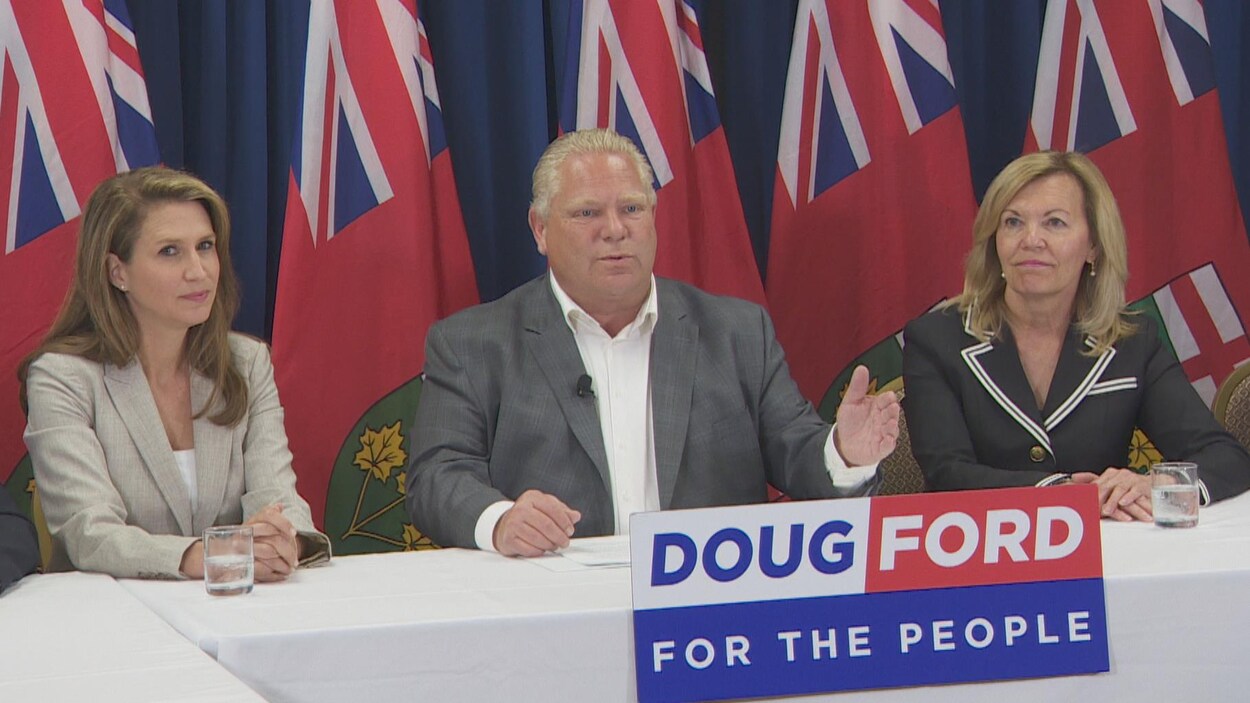Photo de Doug Ford en complet assis à une table entouré de deux femmes