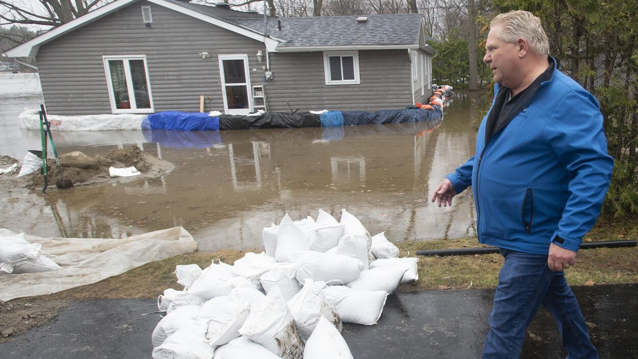 Un homme marchant près d'une zone inondée par une crue printanière.