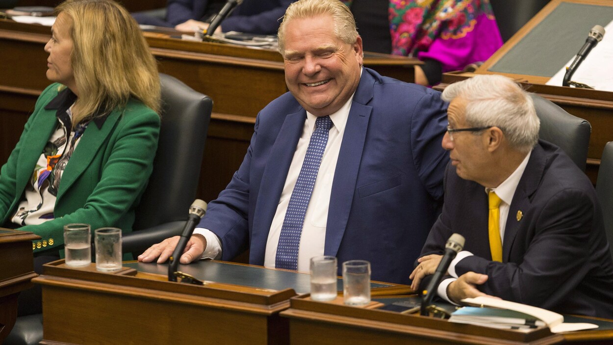 Doug Ford sourit en discutant avec son ministre des Finances, Vic Fedeli.