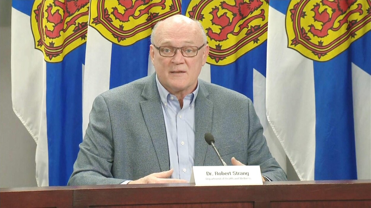 Robert Strang devant des drapeaux de la Nouvelle-Écosse.