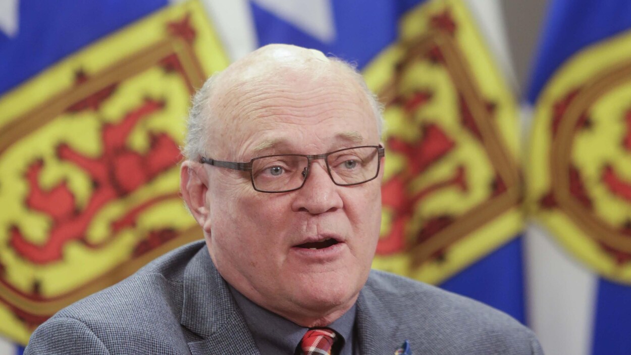 Robert Strang devant des drapeaux de la Nouvelle-Écosse.