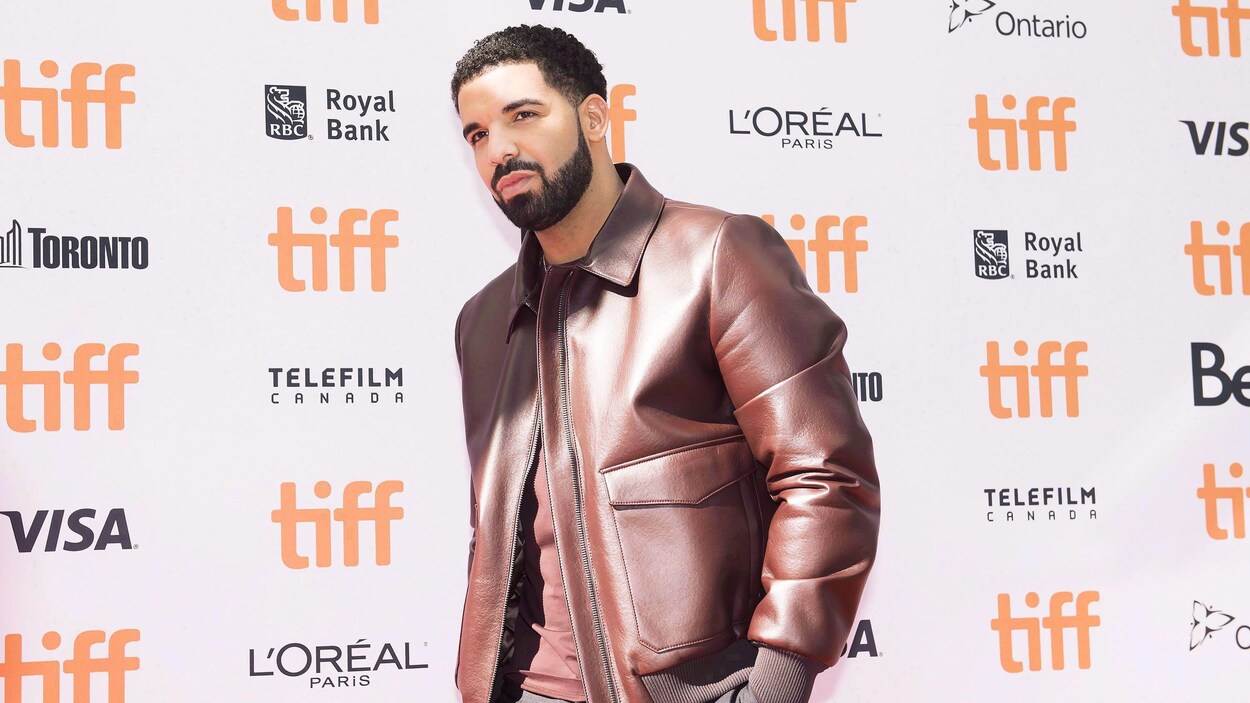 Drake pose devant un mur recouvert de logos du TIFF.