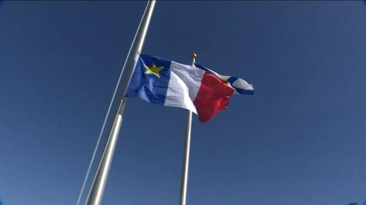 Un drapeau acadien hissé sur un mat de bateau.