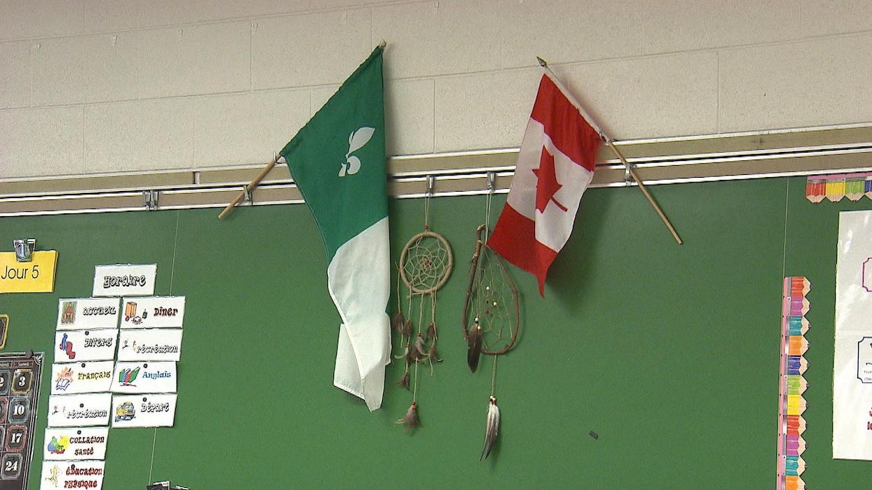 Les drapeaux franco-ontarien et canadien accrochés au-dessus du tableau d'une classe.