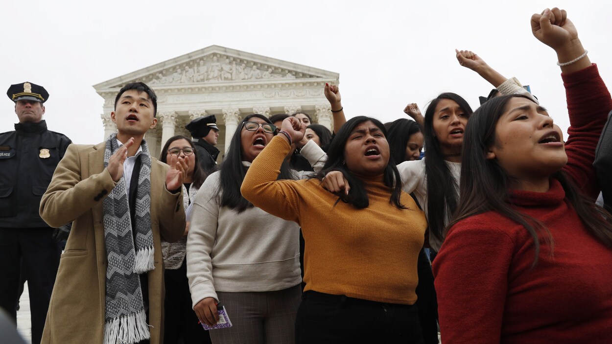 Des manifestants, plusieurs ayant le poing en l'air, se tiennent debout devant la Cour suprême.