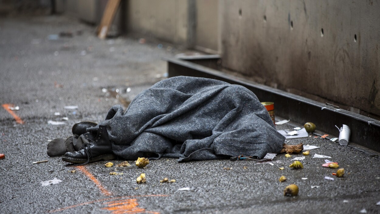 Un homme allongé sous une couverture dans le quartier du Downtown Eastside, à Vancouver.