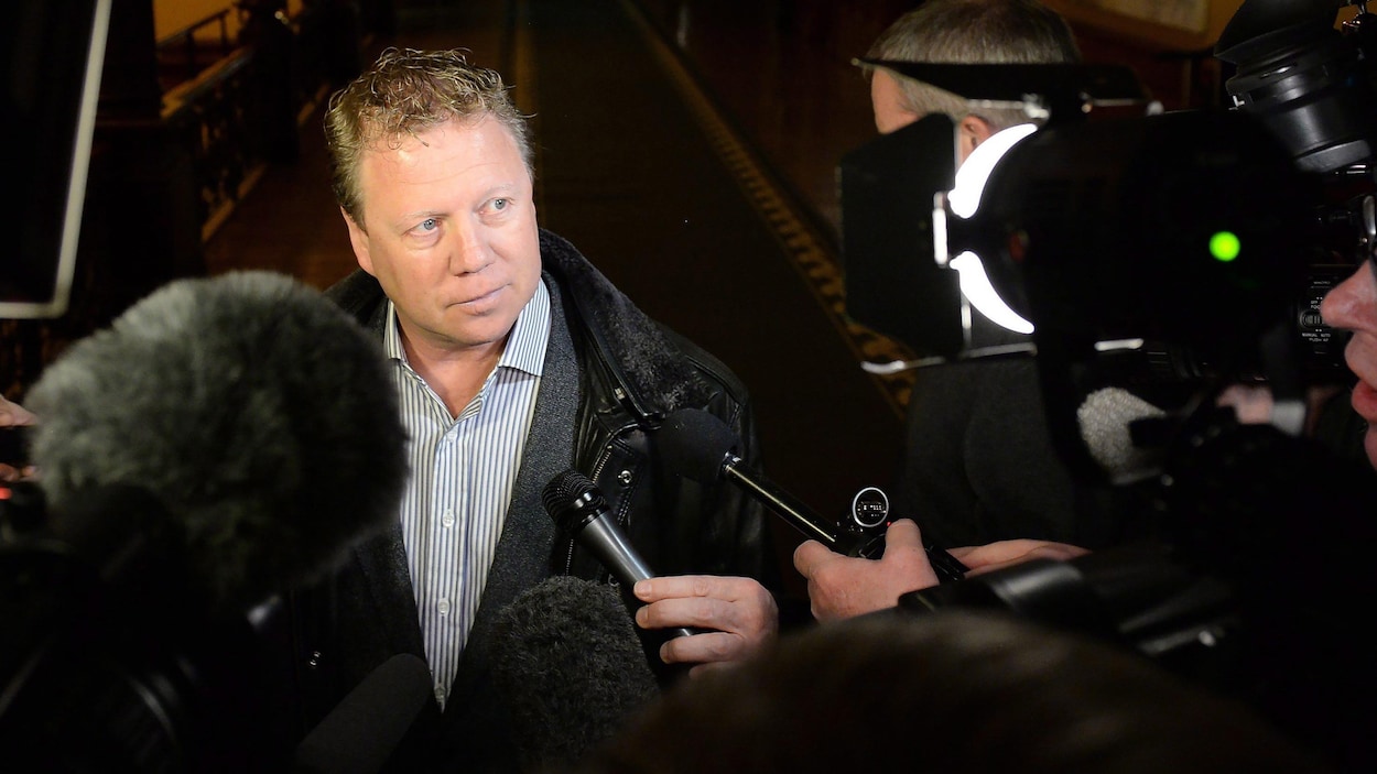 Rick Dykstra entouré des micros de journalistes.