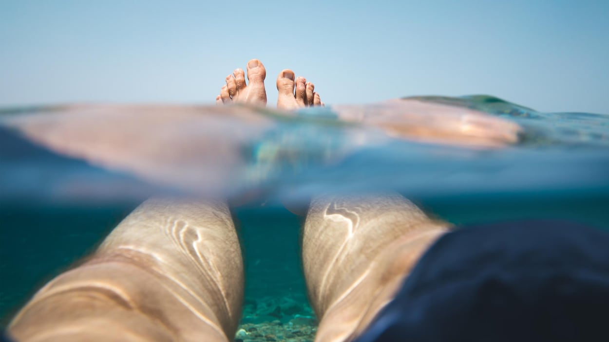 Les pieds d'un homme flottent à la surface de l'océan.