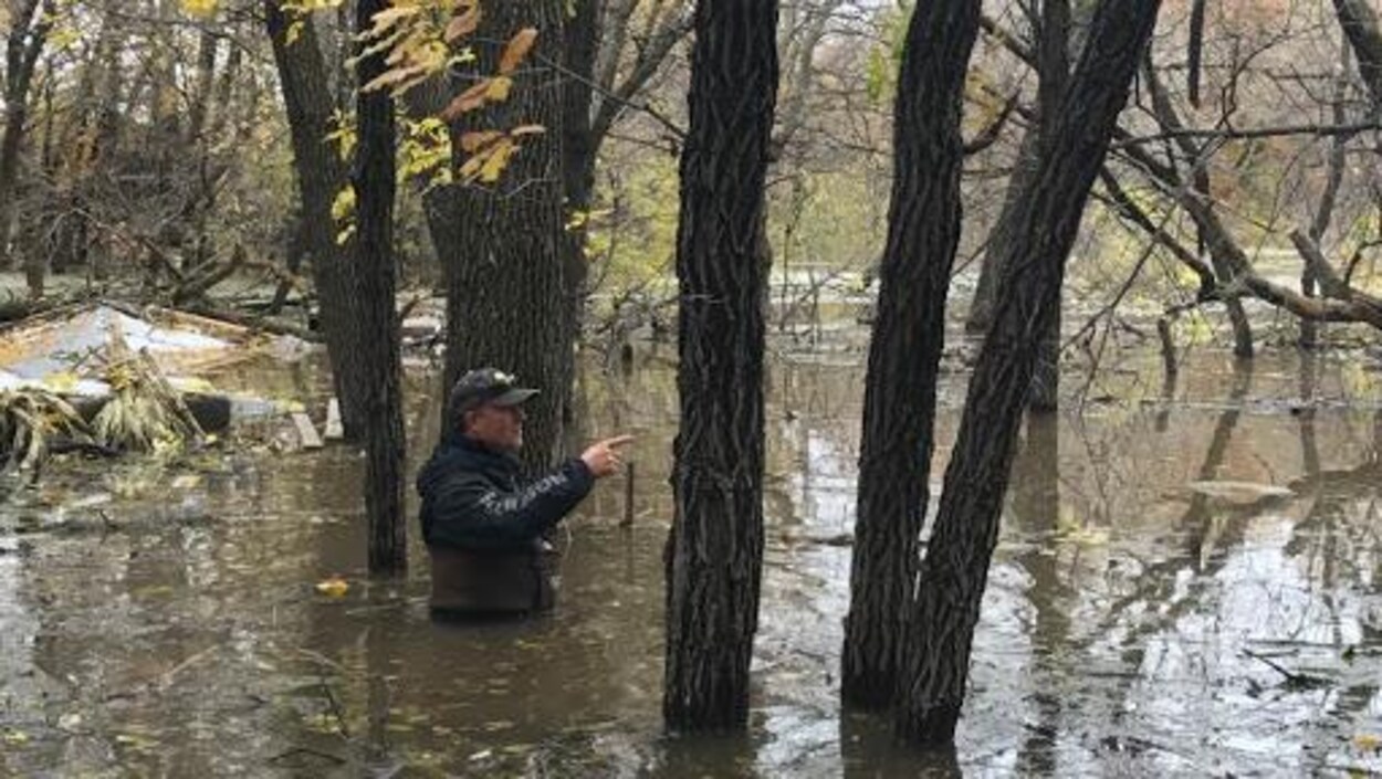 Un homme dans un champ inondé a de l'eau jusqu'à la taille.