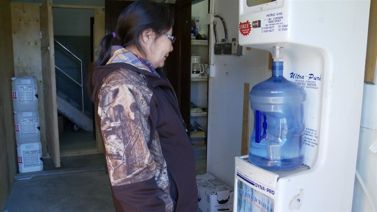 Une femme autochtone remplit un bidon d’eau à une station de remplissage.