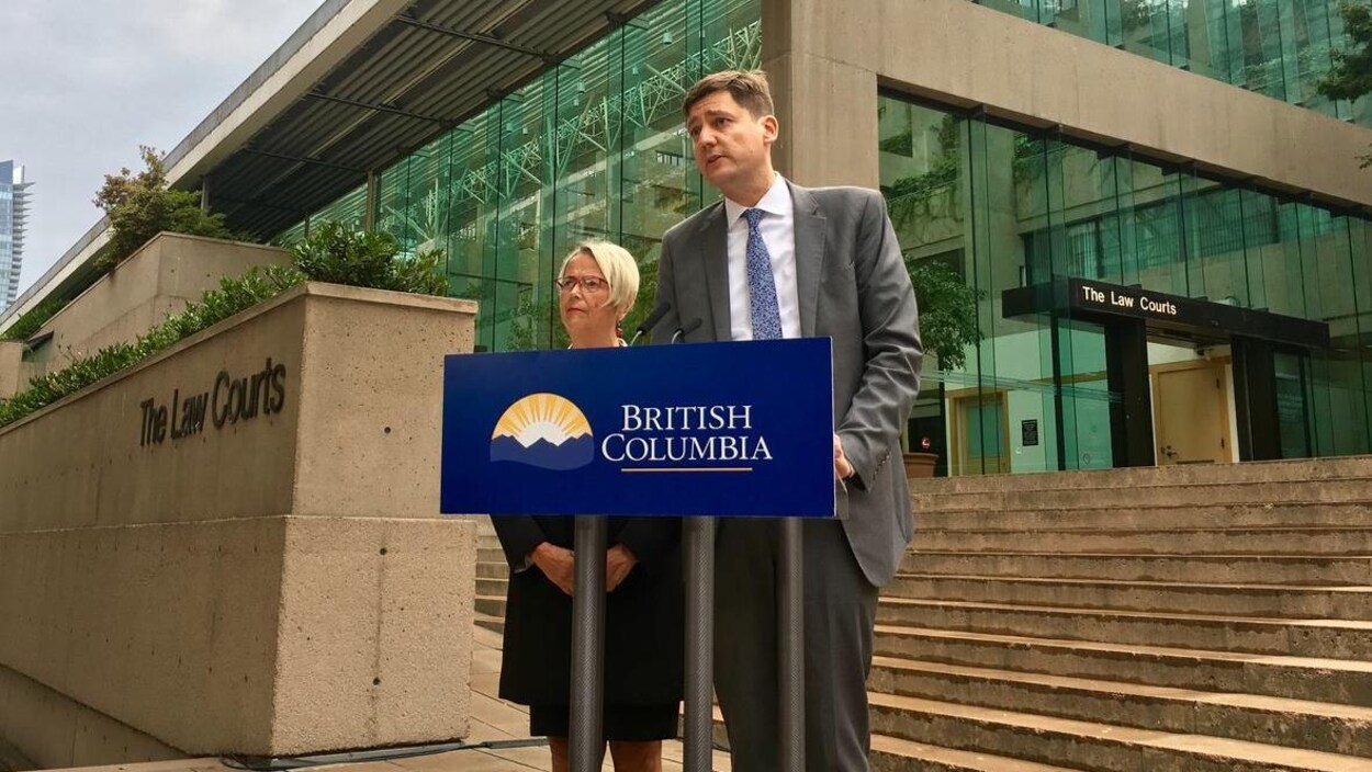 Judy Darcy et David Eby, deux politiciens provinciaux de la Colombie-Britannique devant un lutrin à l'extérieur de la Cour à Vancouver. 