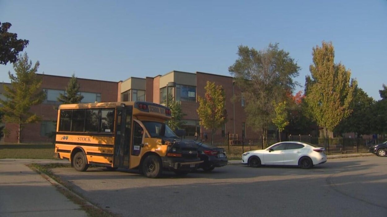 La façade d'un école et un autobus scolaire stationné devant