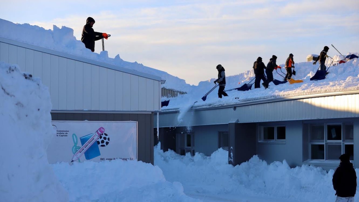 Plusieurs travailleurs s'activent sur le toit de l'école primaire Jules-Émond du secteur Val-Bélair afin que l'établissement scolaire puisse rouvrir ses portes.