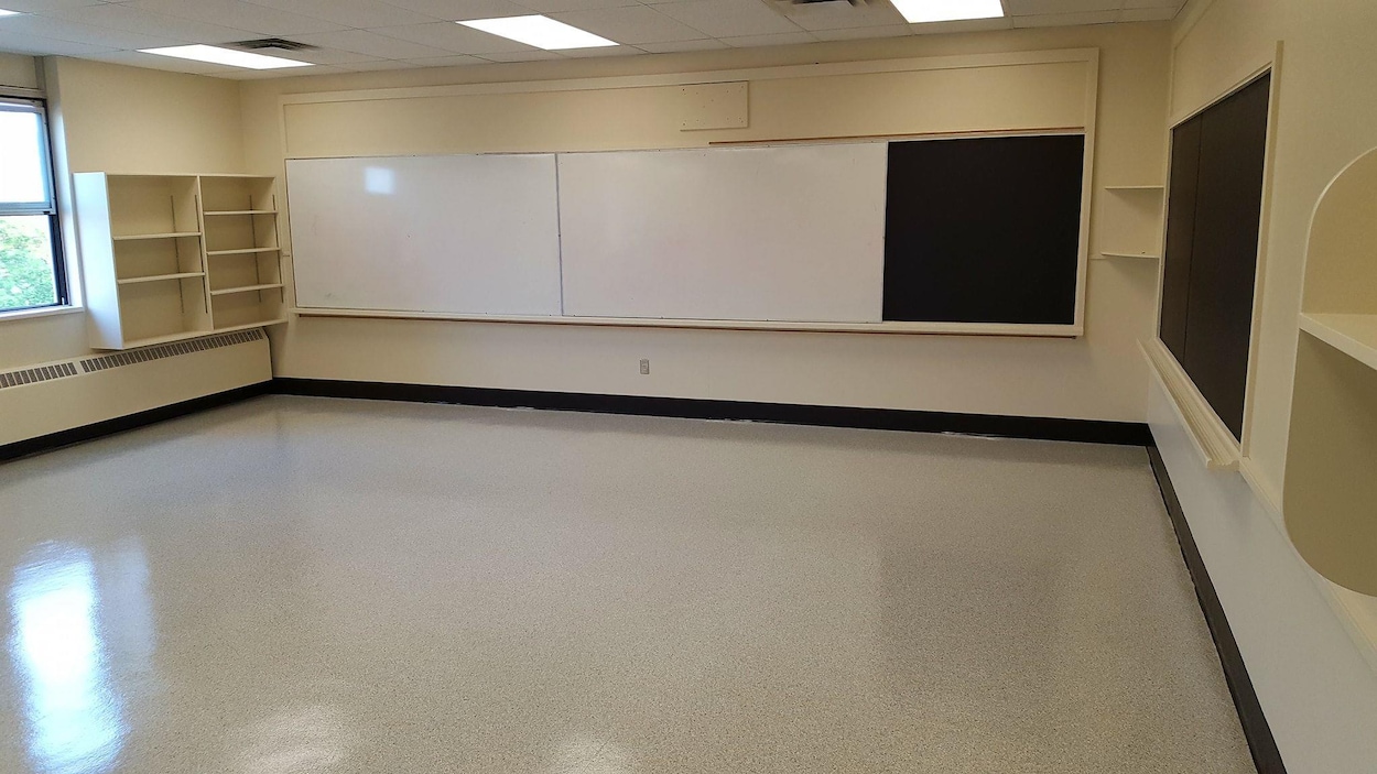 Une classe dans une école, avec des murs beiges et un tableau noir
