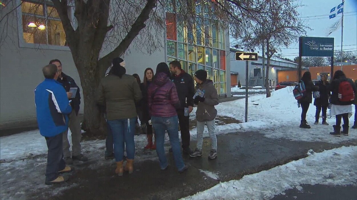 Des gens debout devant l'école.