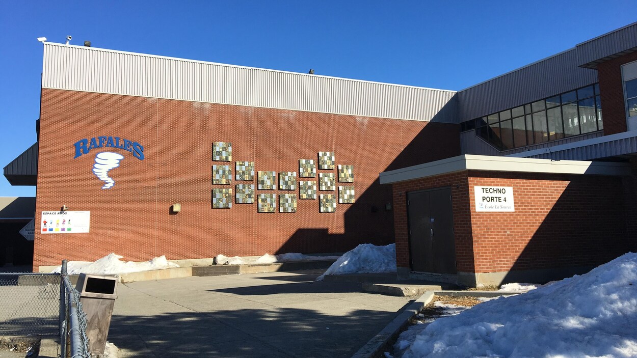 Une école secondaire avec le logo de l'équipe sportives «Les Rafales» sur un mur extérieur.
