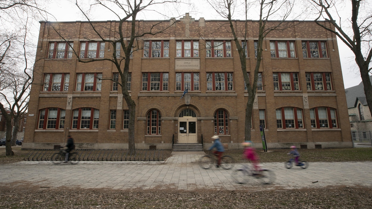 Des gens passent en vélo devant l'école fermée.