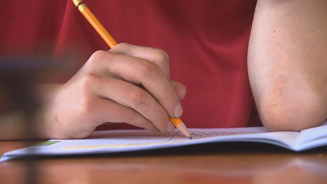Un élève écrit dans un cahier d'exercices.