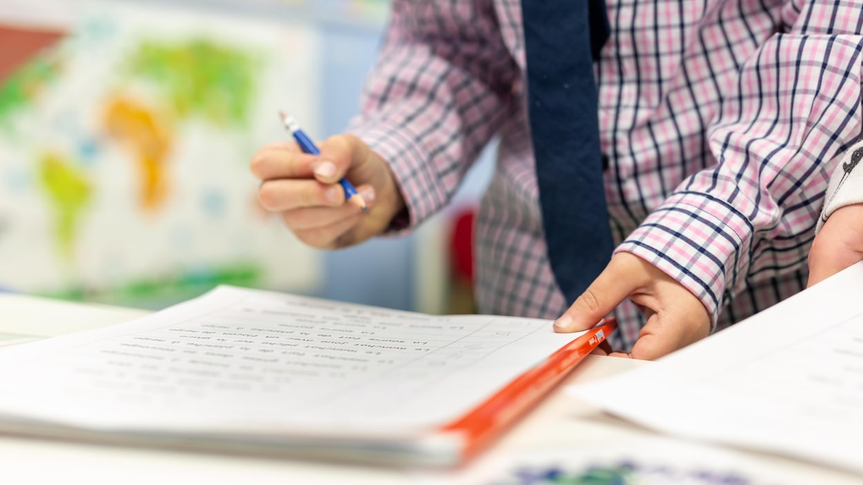 Un enseignant corrige l'exercice d'un élève.