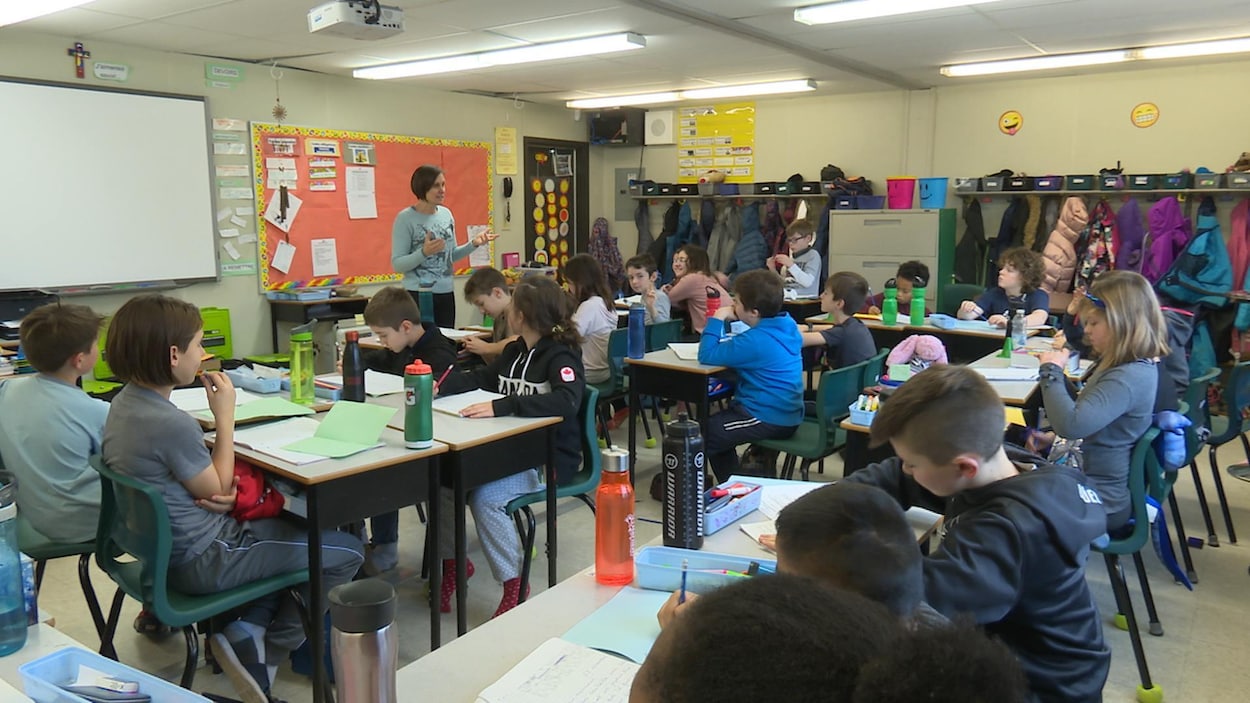 Une vingtaine d'élèves assis dans une salle de classe.