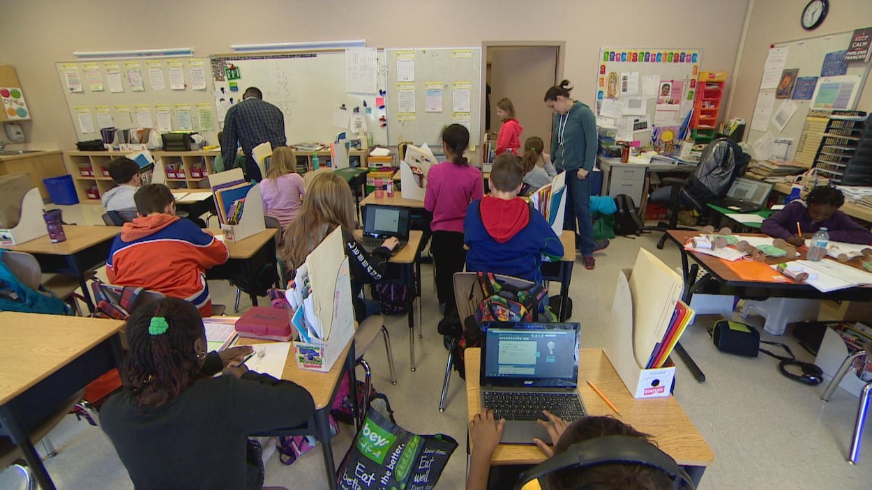 Une salle de classe avec plusieurs élèves du primaire assis à leur bureau.