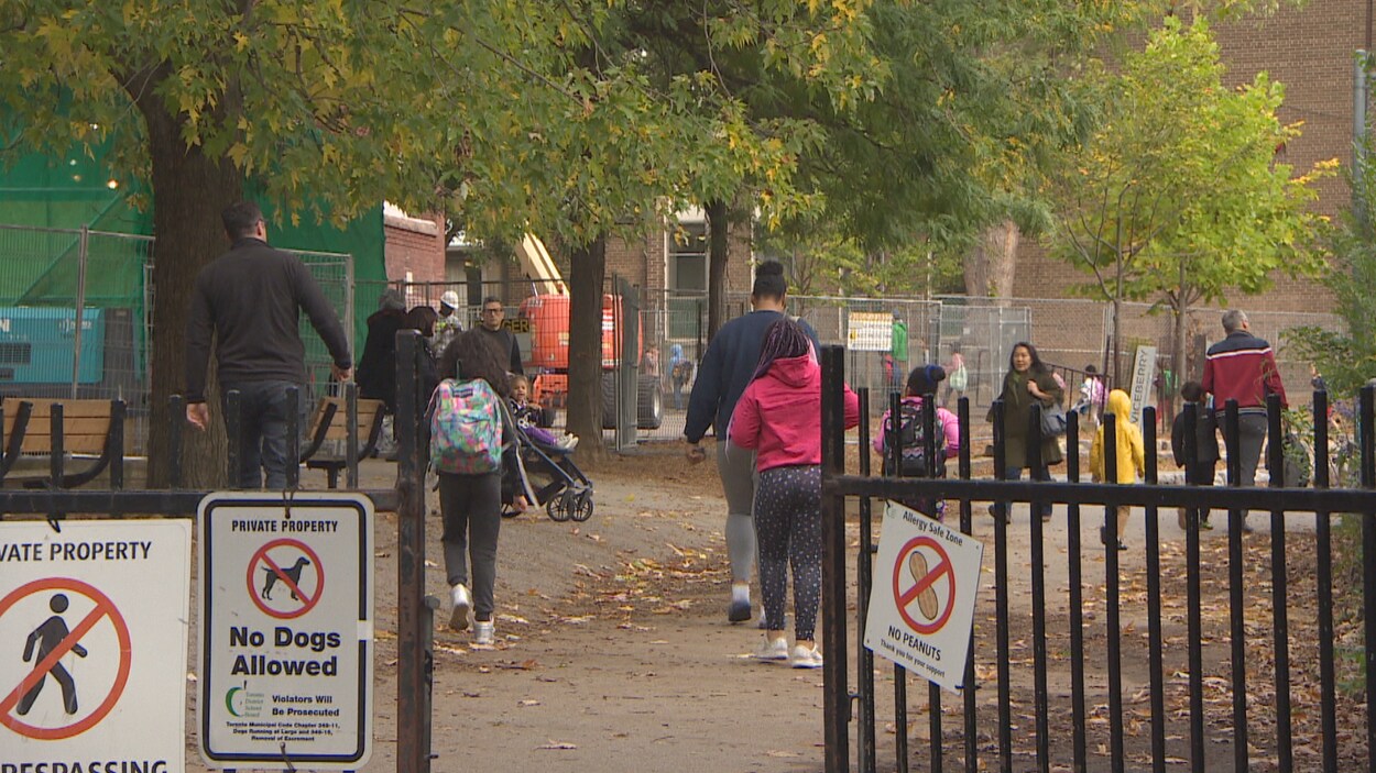 Des enfants et des parents entrent dans une école.