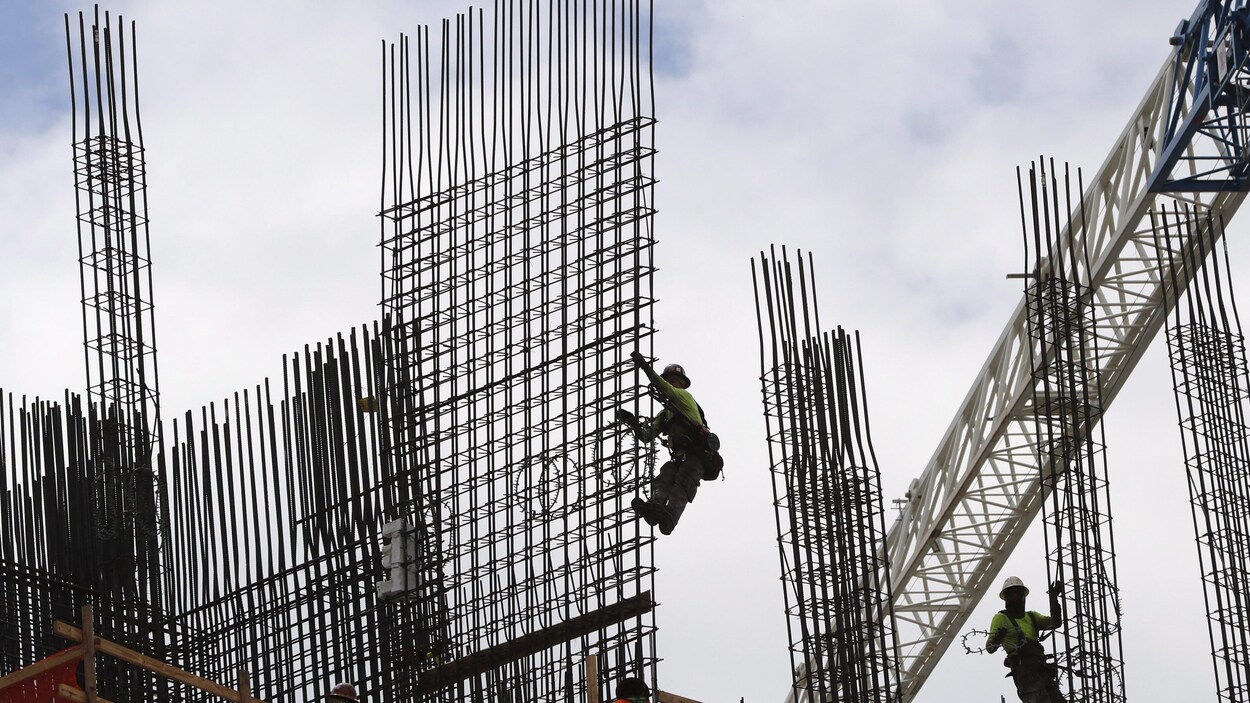 Des ouvriers s'affairent à la construction d'une tour d'habitation.