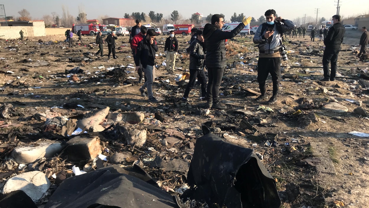 Des gens fouillent les débris au sol à la suite de l'écrasement d'un avion.