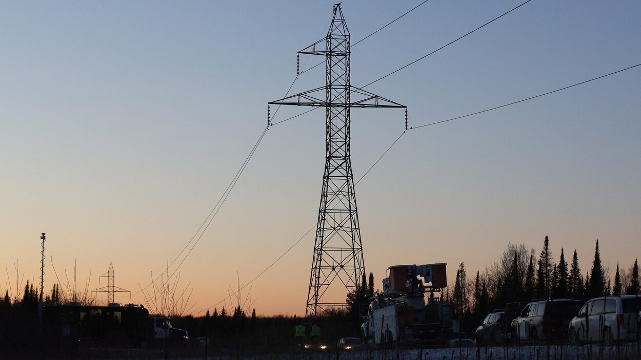 Des véhicules au pied d'un pylône électrique à la tombée de la nuit. Des véhicules au pied d'un pylône électrique à la tombée de la nuit.