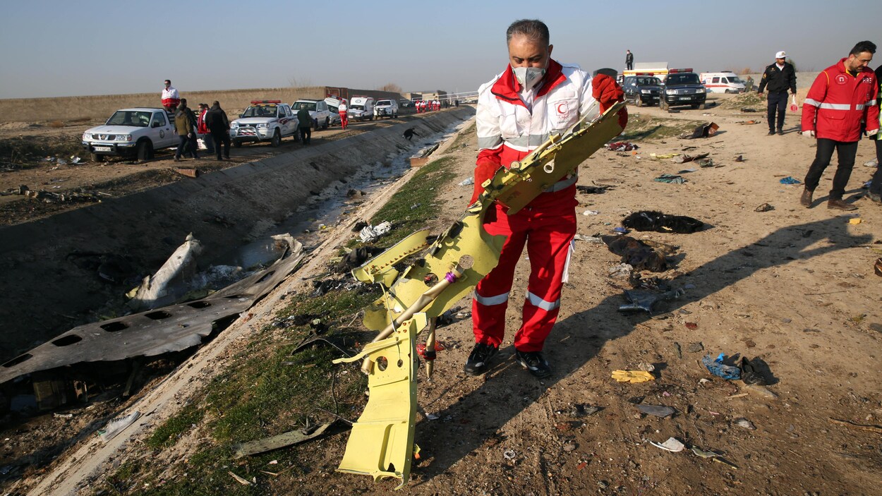 Un membre de l'équipe de secours ramasse un fragment de l'appareil.