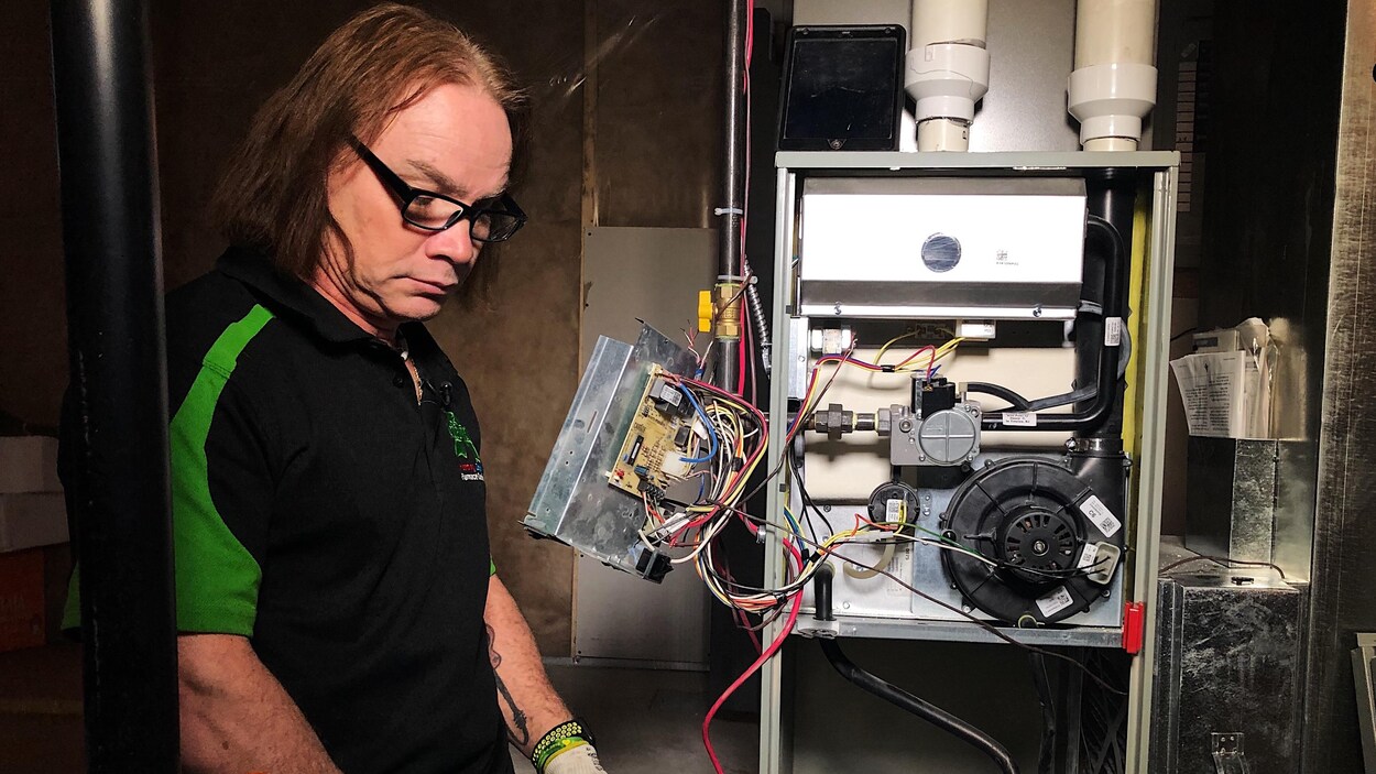Un technicien observe une chaudière dont la boîte de contrôle est ouverte.
