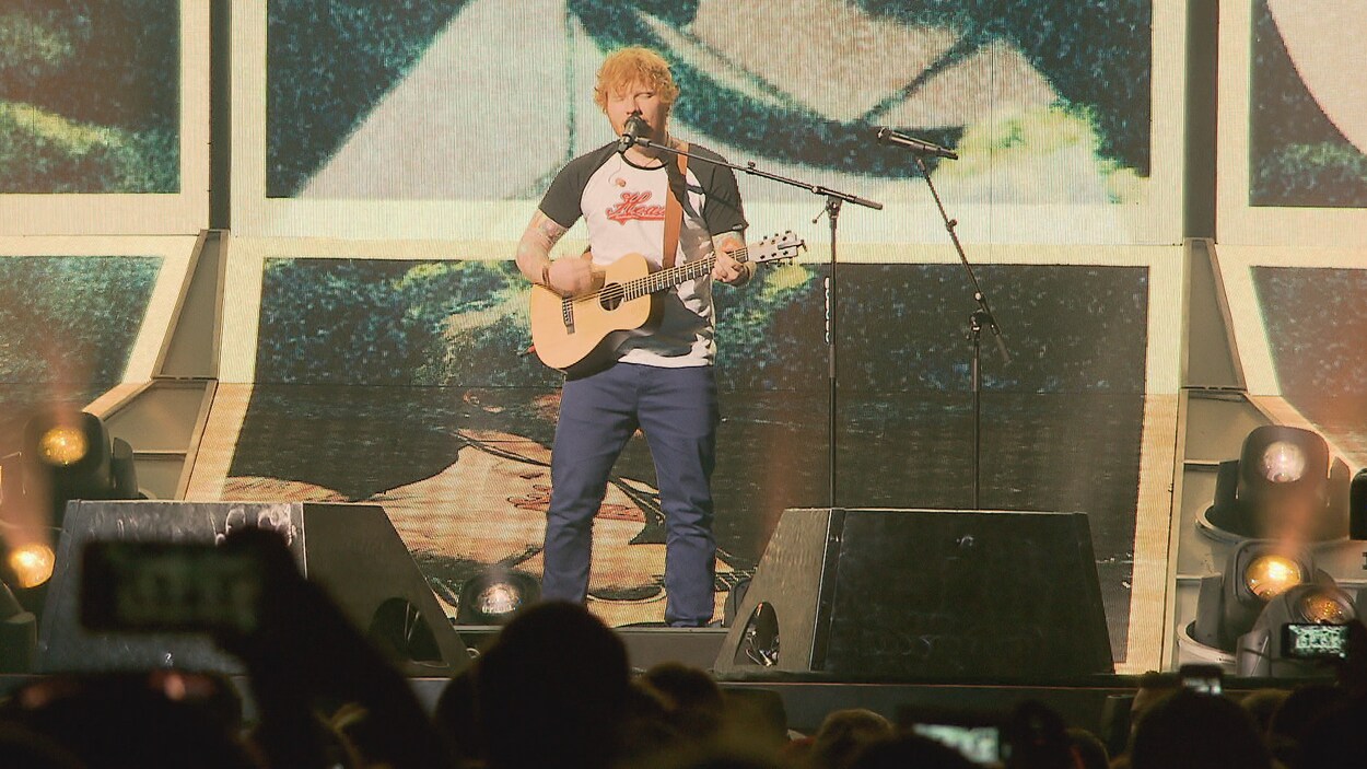 Ed Sheeran joue de la guitare et chante sur scène.